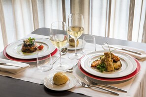 Una mesa de comedor lista con platos de comida, copas de vino y cubiertos.