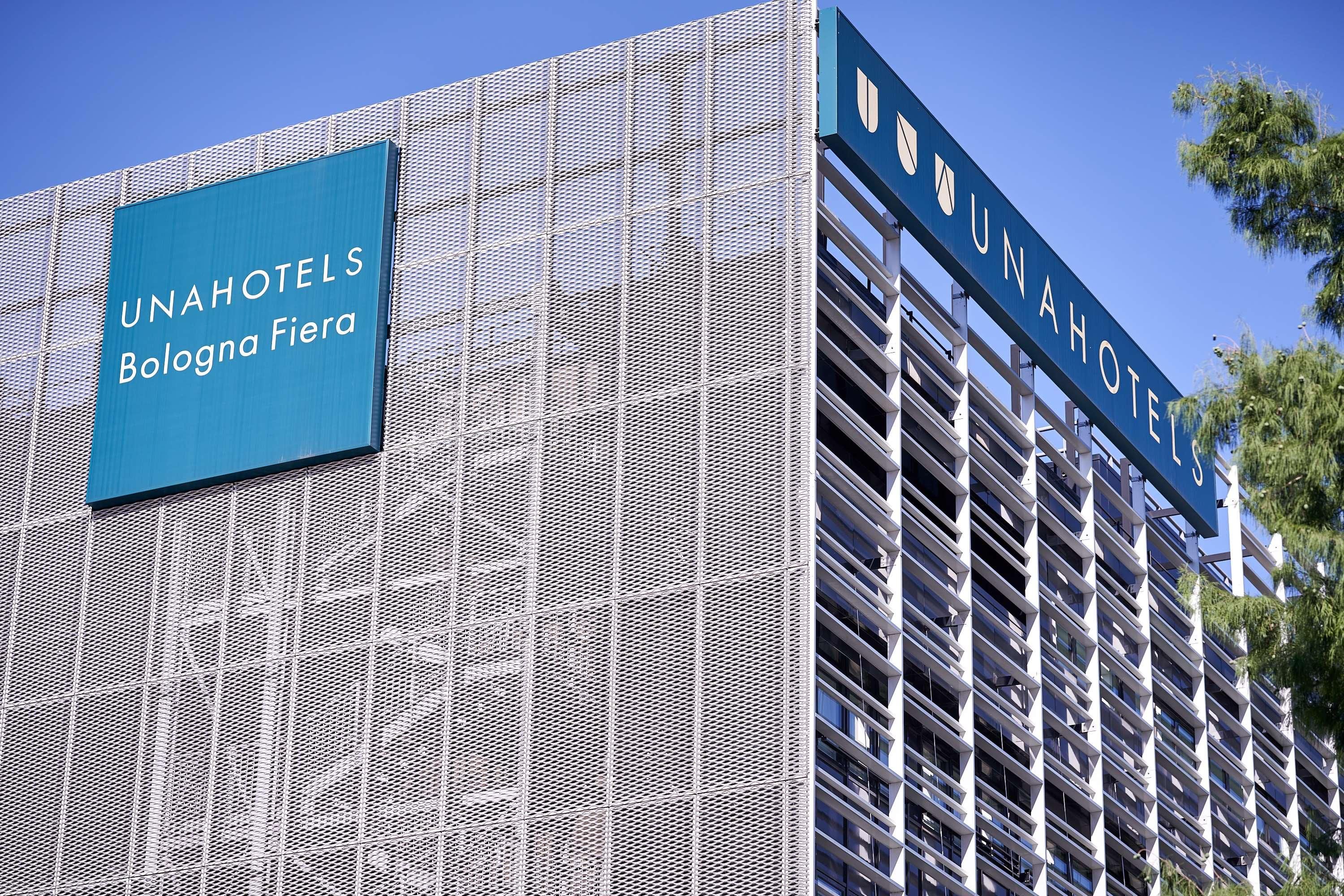 A building with a sign reading 'UNAHOTELS Bologna Fiera' and a modern architectural design with a grid-like facade.