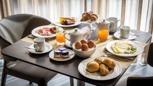 Una mesa de desayuno con platos de huevos, tostadas, pasteles y jugo.