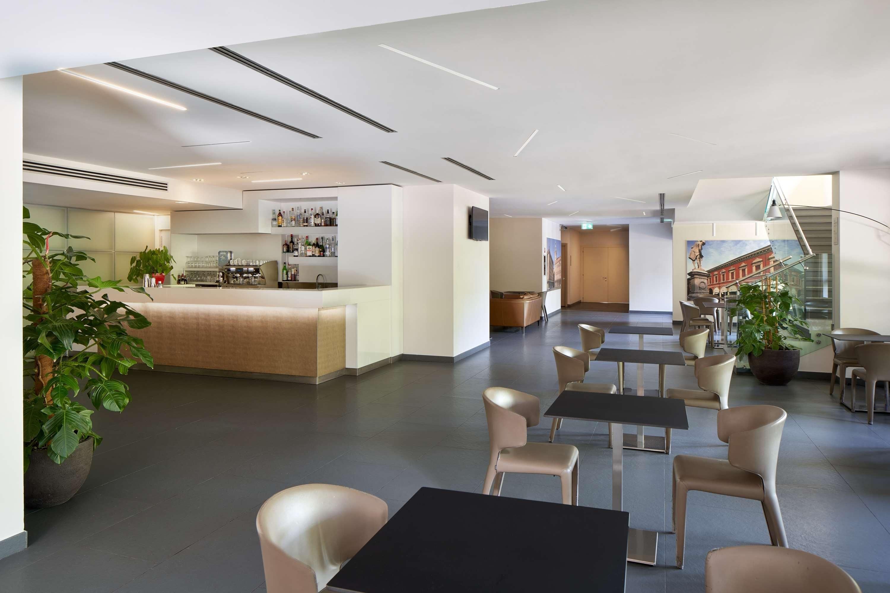 Una moderna hall d'albergo con area bar, posti a sedere e una scala.