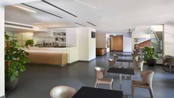 Una moderna hall d'albergo con area bar, posti a sedere e una scala.