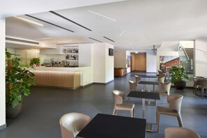 Un moderno vestíbulo de hotel con una zona de bar, asientos y una escalera.