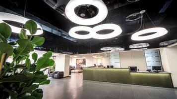 A modern reception area with a green counter, seating, and a ceiling with circular light fixtures.