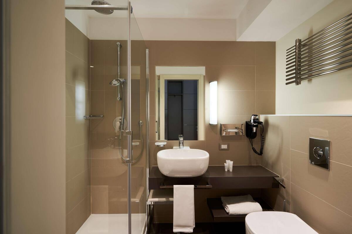 Un baño moderno con ducha envuelta en vidrio, un lavabo blanco y un inodoro.