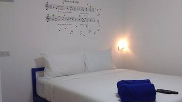 A single bed with white bedding and a blue frame, a wall-mounted light, and a poster with musical notes.