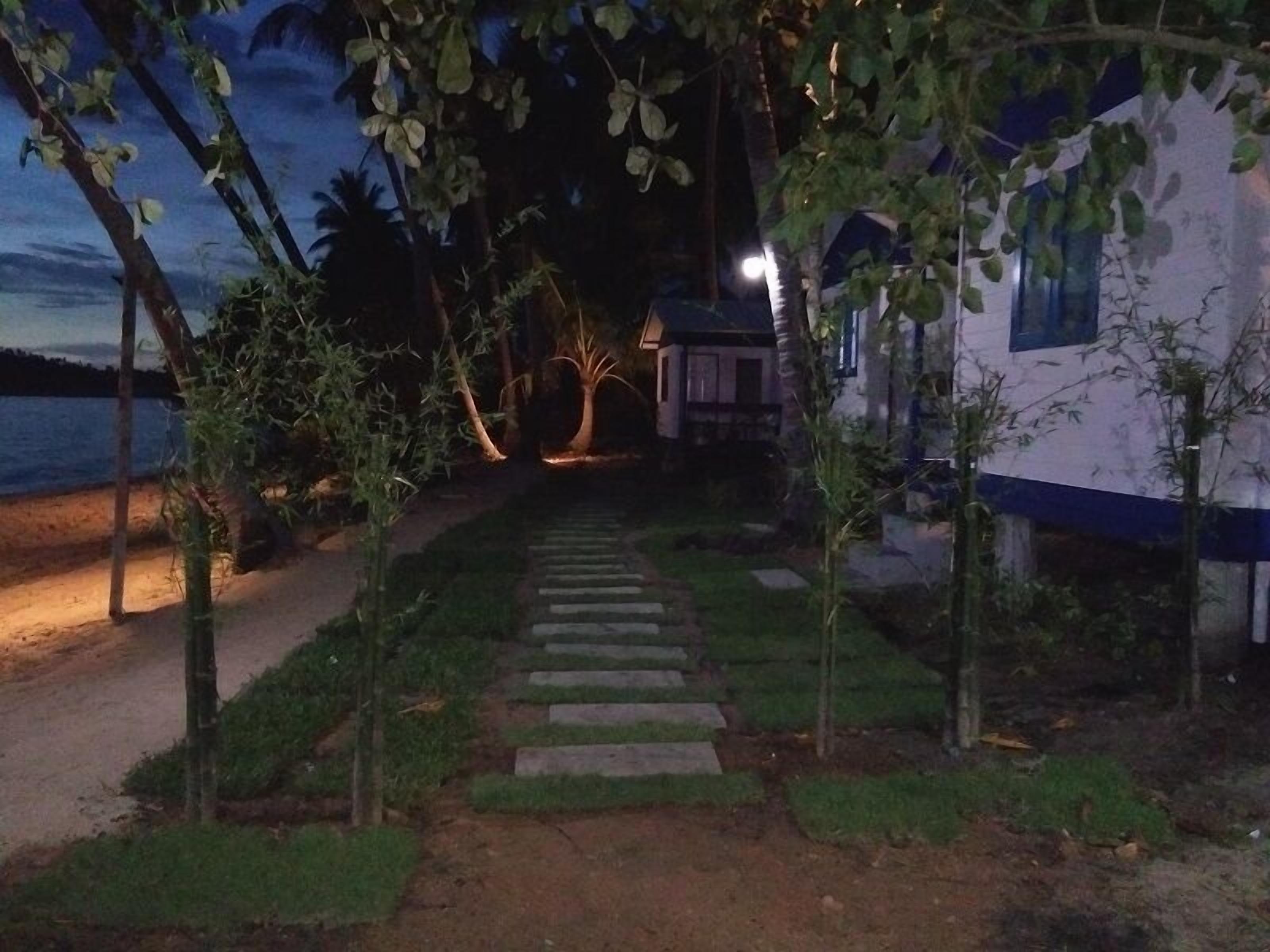 A pathway leading to a house with a view of the sea at dusk.