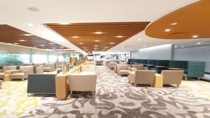 Un hall d’hôtel spacieux, doté de plusieurs espaces salon, d’un tapis à motifs et d’un design de plafond moderne.