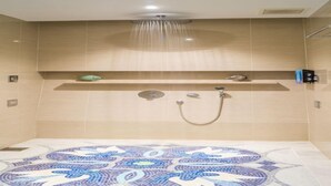 Un espace douche moderne avec un carrelage à motifs, une étagère murale agrémentée d’objets décoratifs et une paroi de douche en verre.