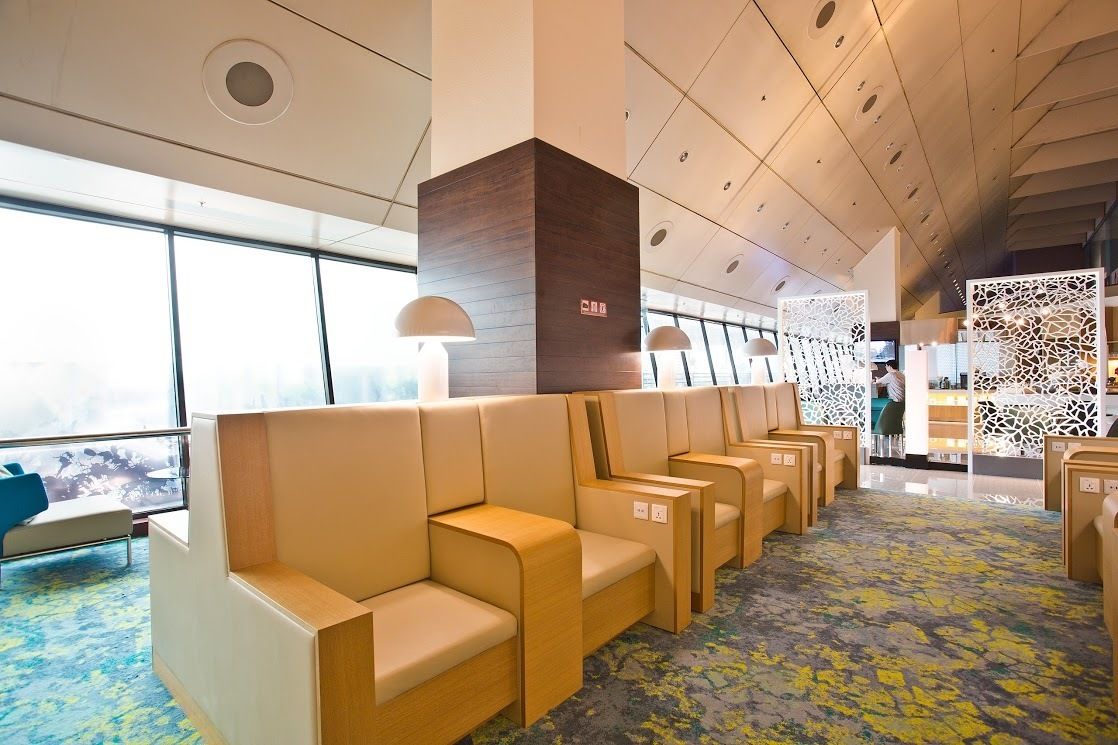 A modern hotel lobby with a row of beige sofas, a reception desk, and a decorative partition.