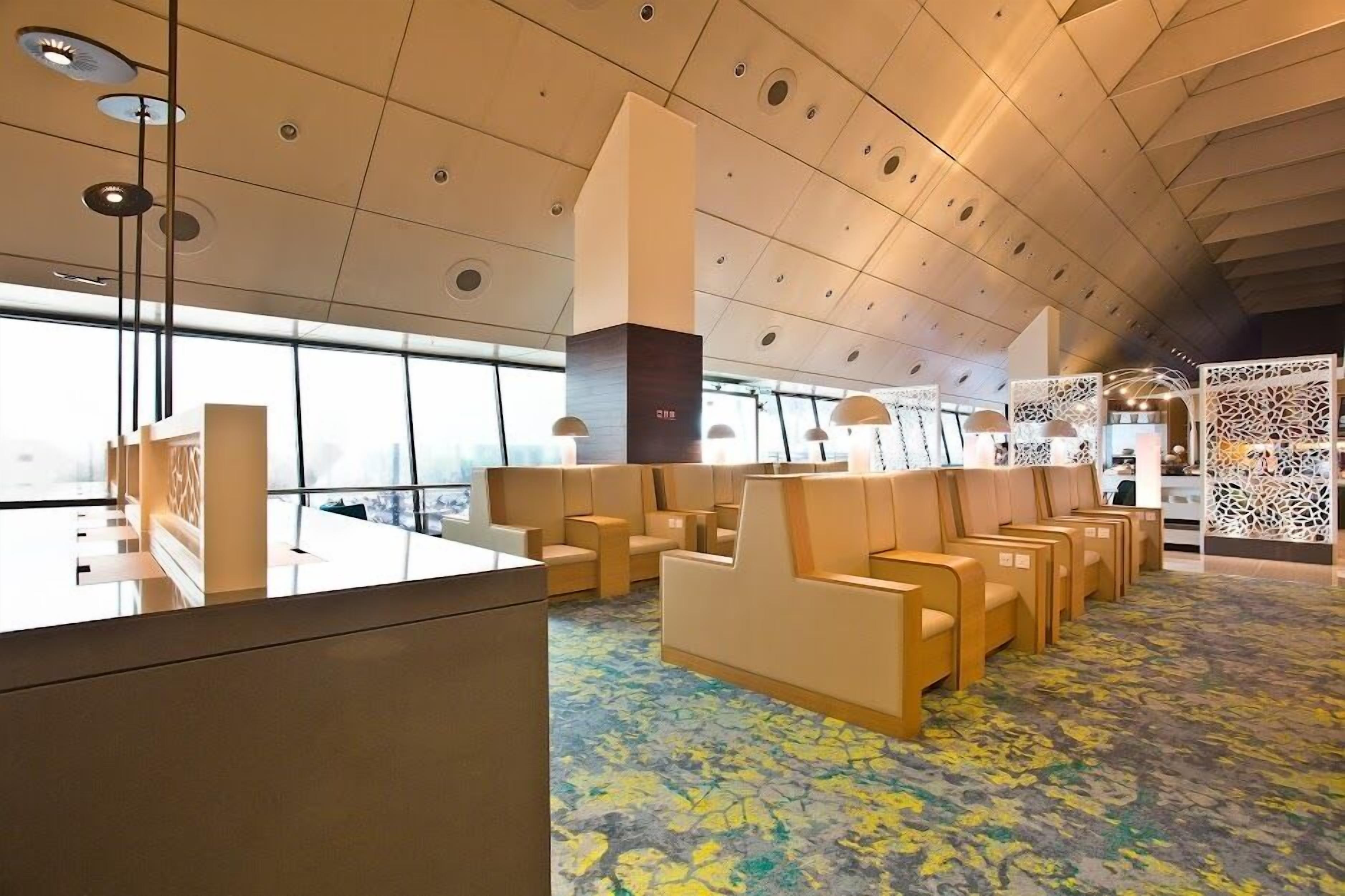 A modern hotel lobby with a reception desk, seating area, and large windows.