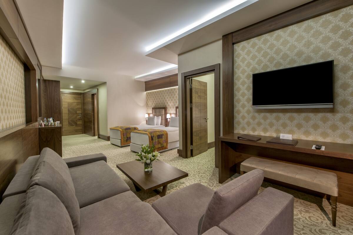 A hotel room with a sofa, a coffee table, a TV, a desk, and a bed.