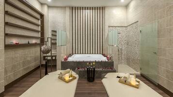 Un cuarto de spa con una bañera grande, dos camillas de masaje y una pared decorativa con estantes.