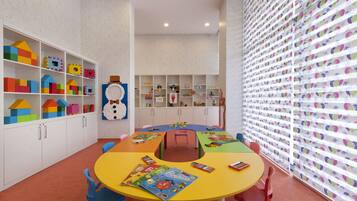 Children can engage in activities at the central table surrounded by chairs, with building blocks and toys available for play.