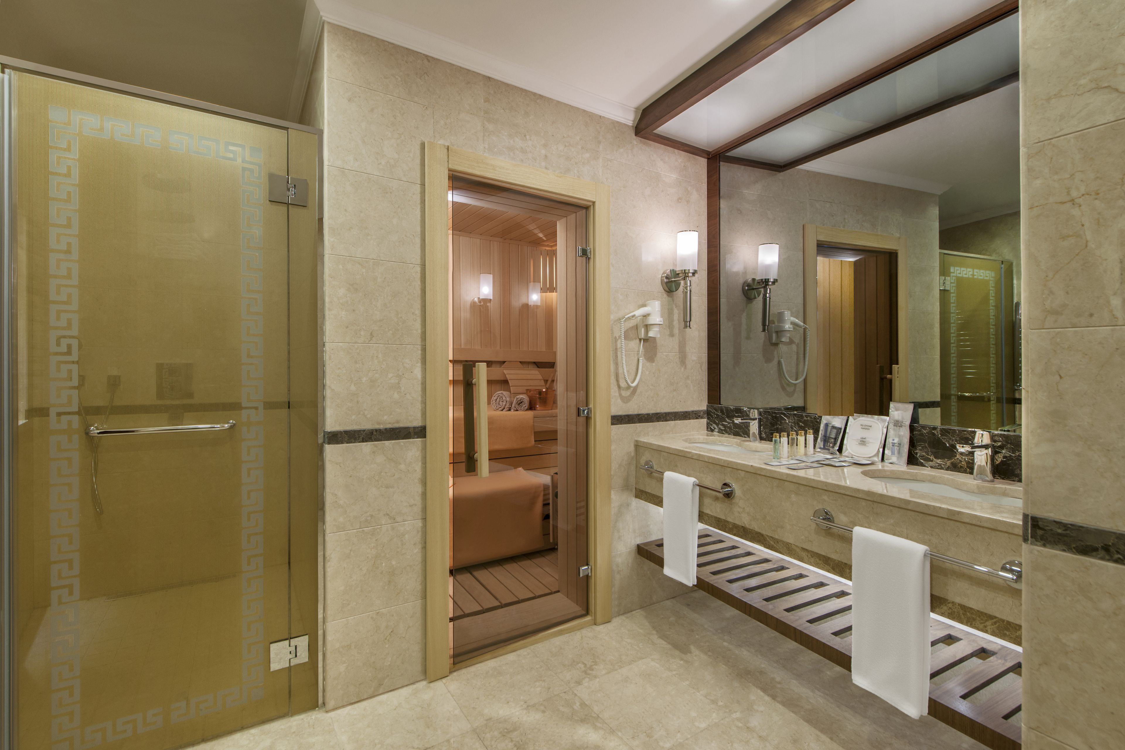 A modern bathroom with a sauna, a large mirror, and a vanity with toiletries.
