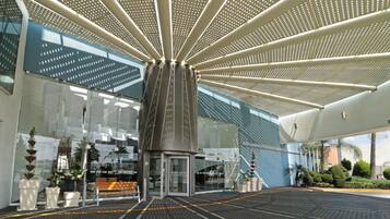 A modern building entrance with a glass facade, a central column, and a patterned ceiling.