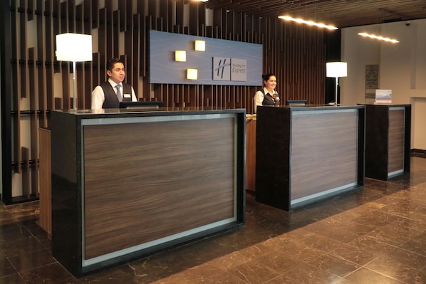 Un área de recepción de diseño moderno, con un mostrador, un cartel en la pared y un panel de madera de fondo.