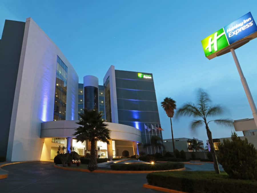 Ein modernes Hotel mit einem Holiday Inn Express Schild, das eine geschwungene Fassade, große Fenster und einen gut beleuchteten Eingang aufweist.