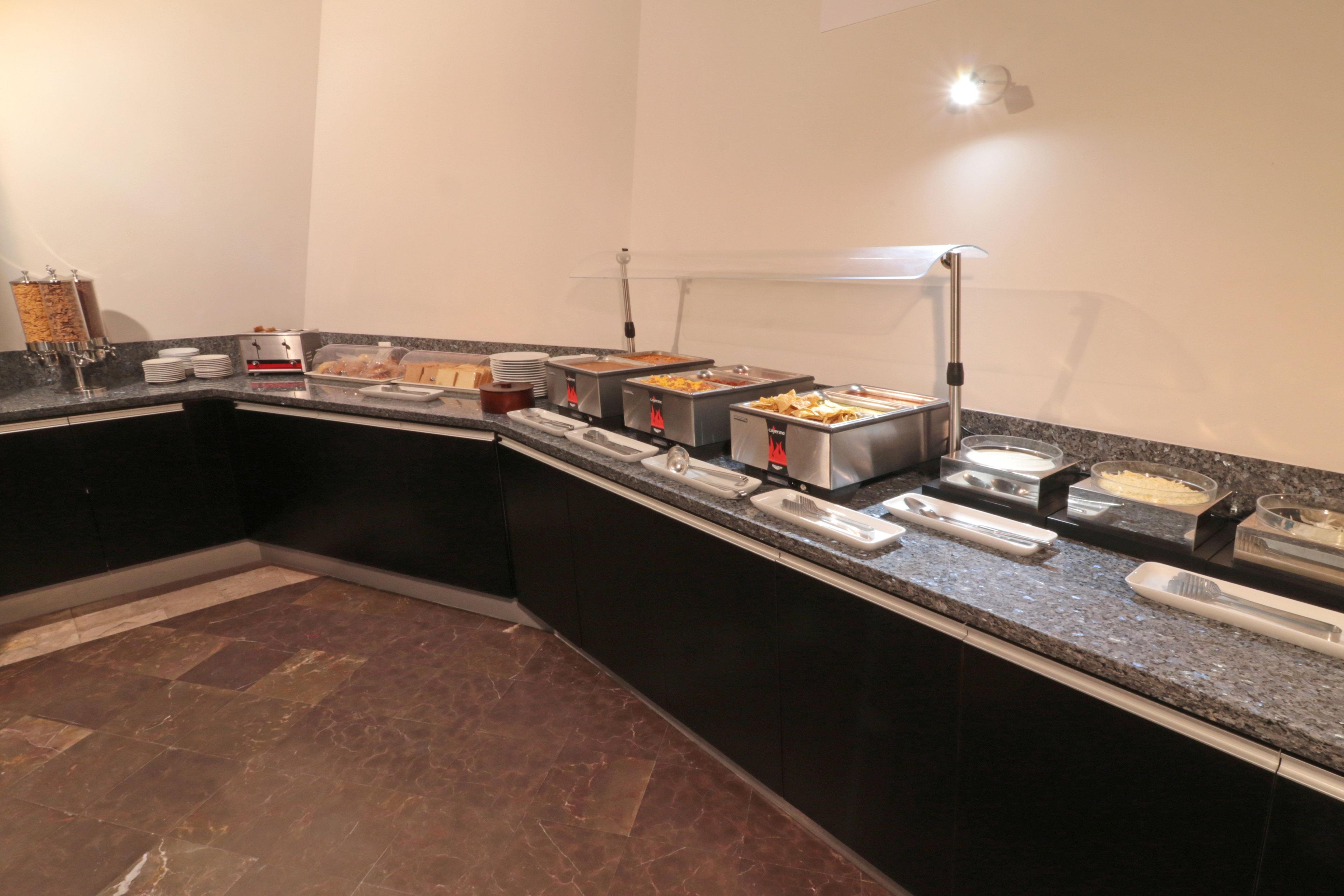 A buffet setup with various food stations, a marble-tiled floor, and a modern kitchen layout.