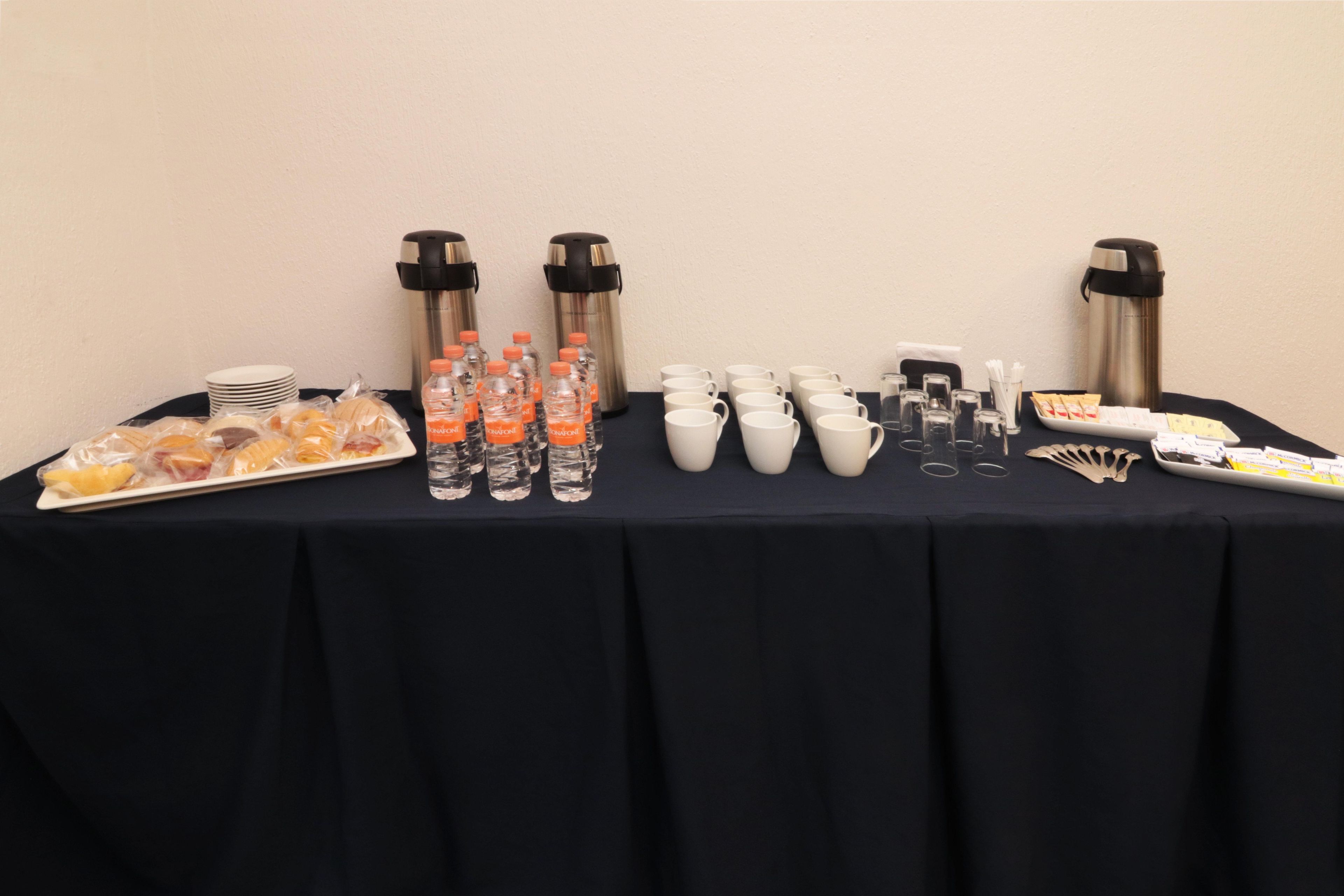 A table with food, water bottles, cups, and thermos flasks.