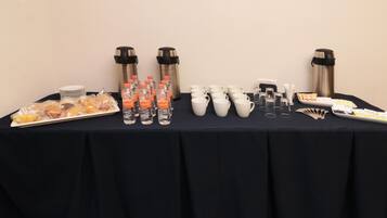 A table with food, water bottles, cups, and thermos flasks.