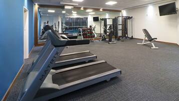 A gym with treadmills, weight machines, and a bench.