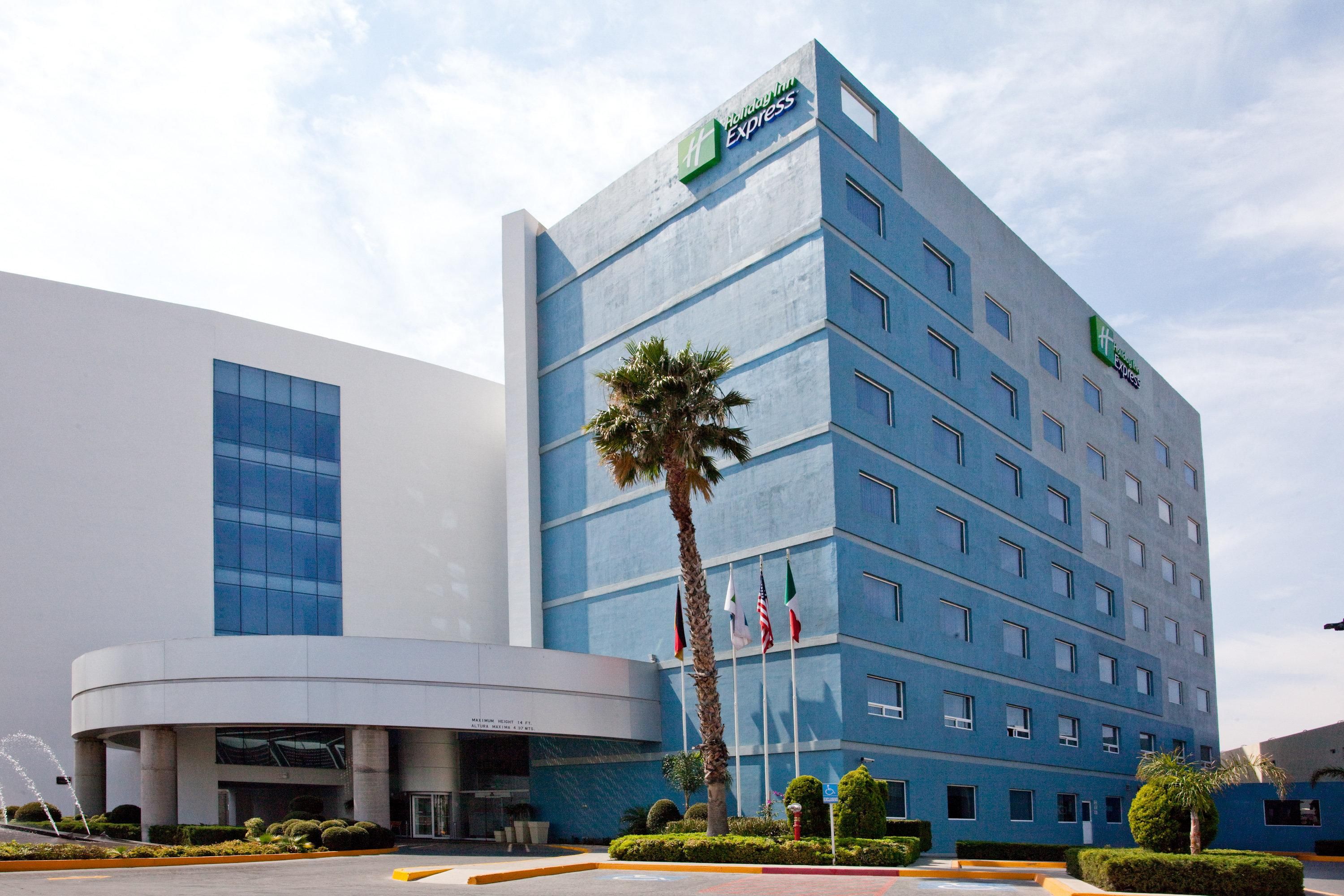 A modern hotel building with a prominent Express logo, multiple floors, and a well-maintained garden area.