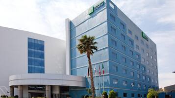 A modern hotel building with a prominent Express logo, multiple floors, and a well-maintained garden area.