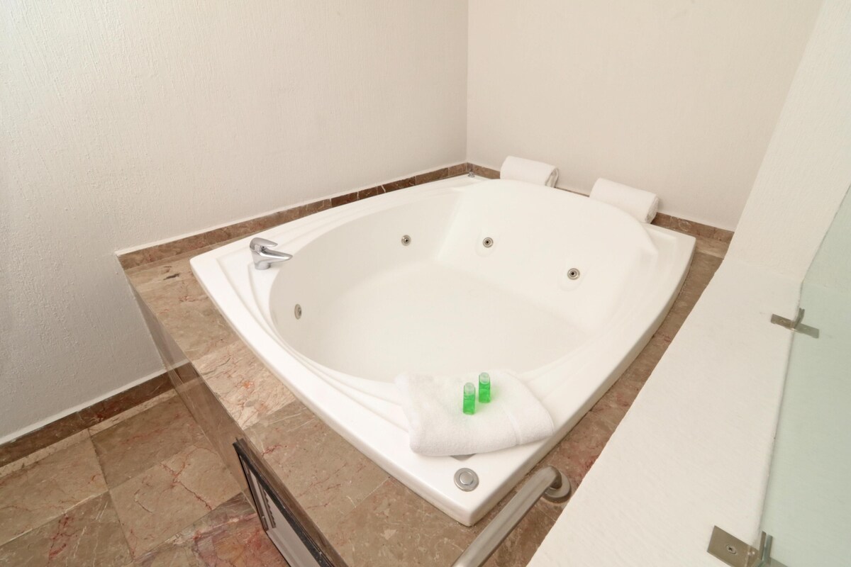 Un baño moderno con una bañera independiente, un box de ducha con mampara de vidrio y suelo de mármol.