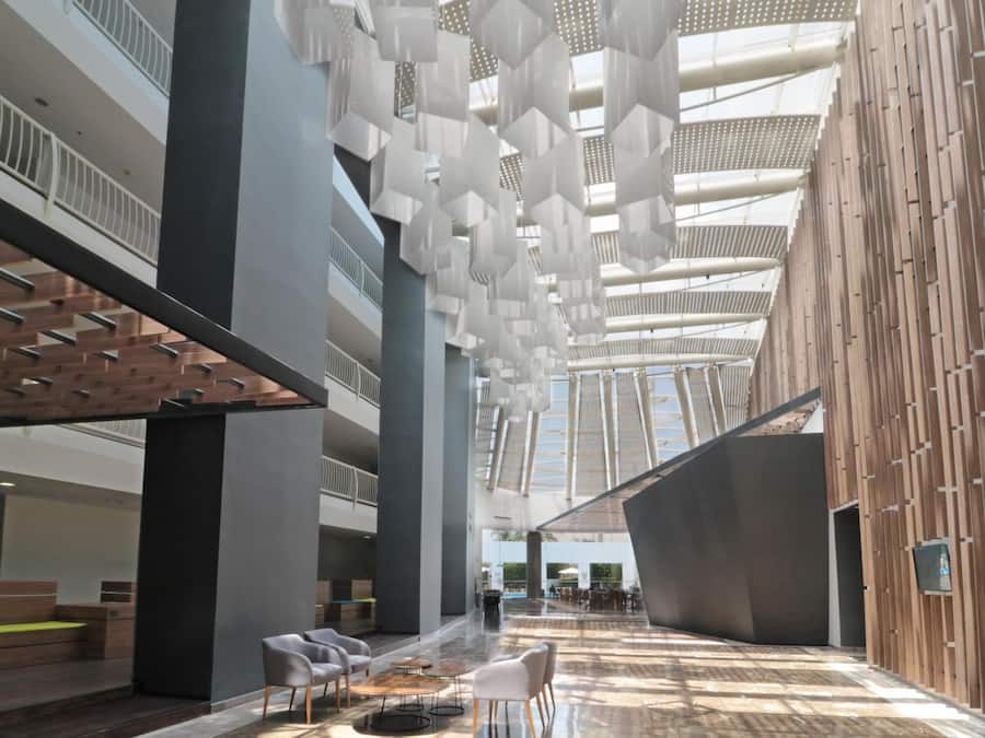 Un amplio atrium con techos altos, mobiliario moderno y una zona de estar central.