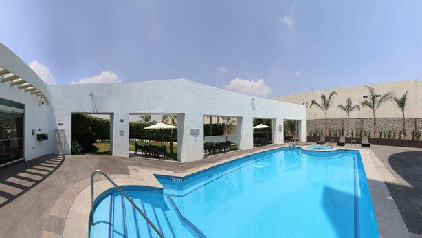 Ein modernes Gebäude mit Swimmingpool, Glasüren und Palmen.