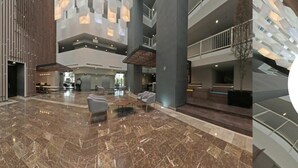 En rymlig entréhall med högt i tak, marmorgolv och moderna möbler.