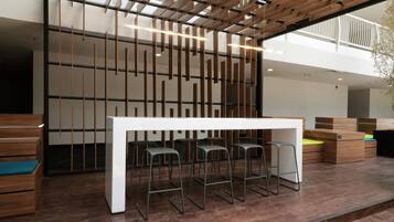 A modern interior with a white table and bar stools, wooden partitions, and a mezzanine level.