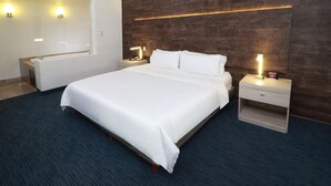 Ein Hotelzimmer mit einem großen Bett, Nachttischen, einem Schminktisch und Wandlampen.