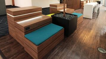 A modern reception area with wooden furniture, a potted plant, and a seating area with teal cushions.