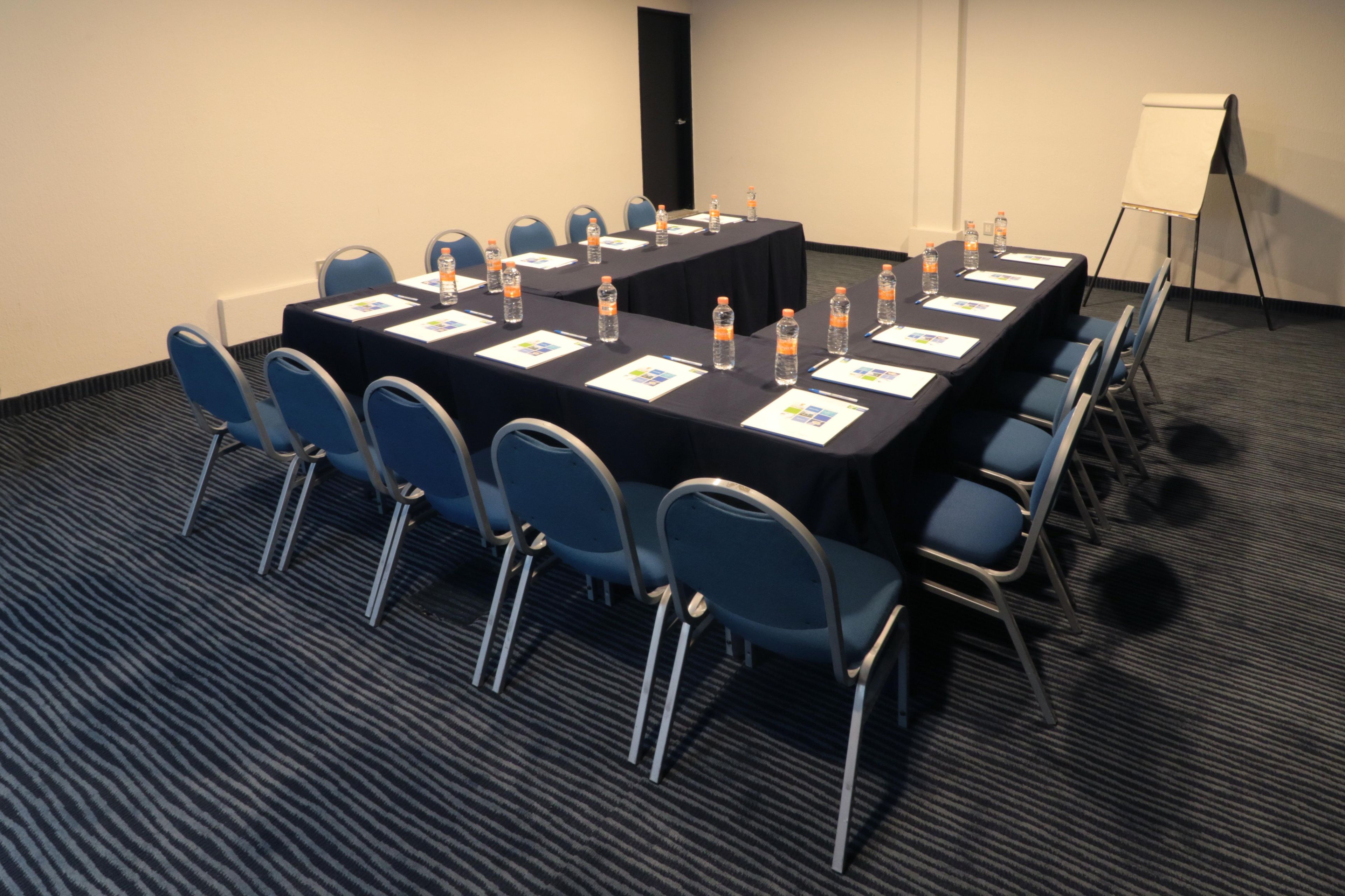 A conference room with a long table, chairs, water bottles, and a whiteboard.