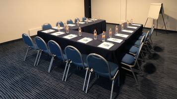 A conference room with a long table, chairs, water bottles, and a whiteboard.