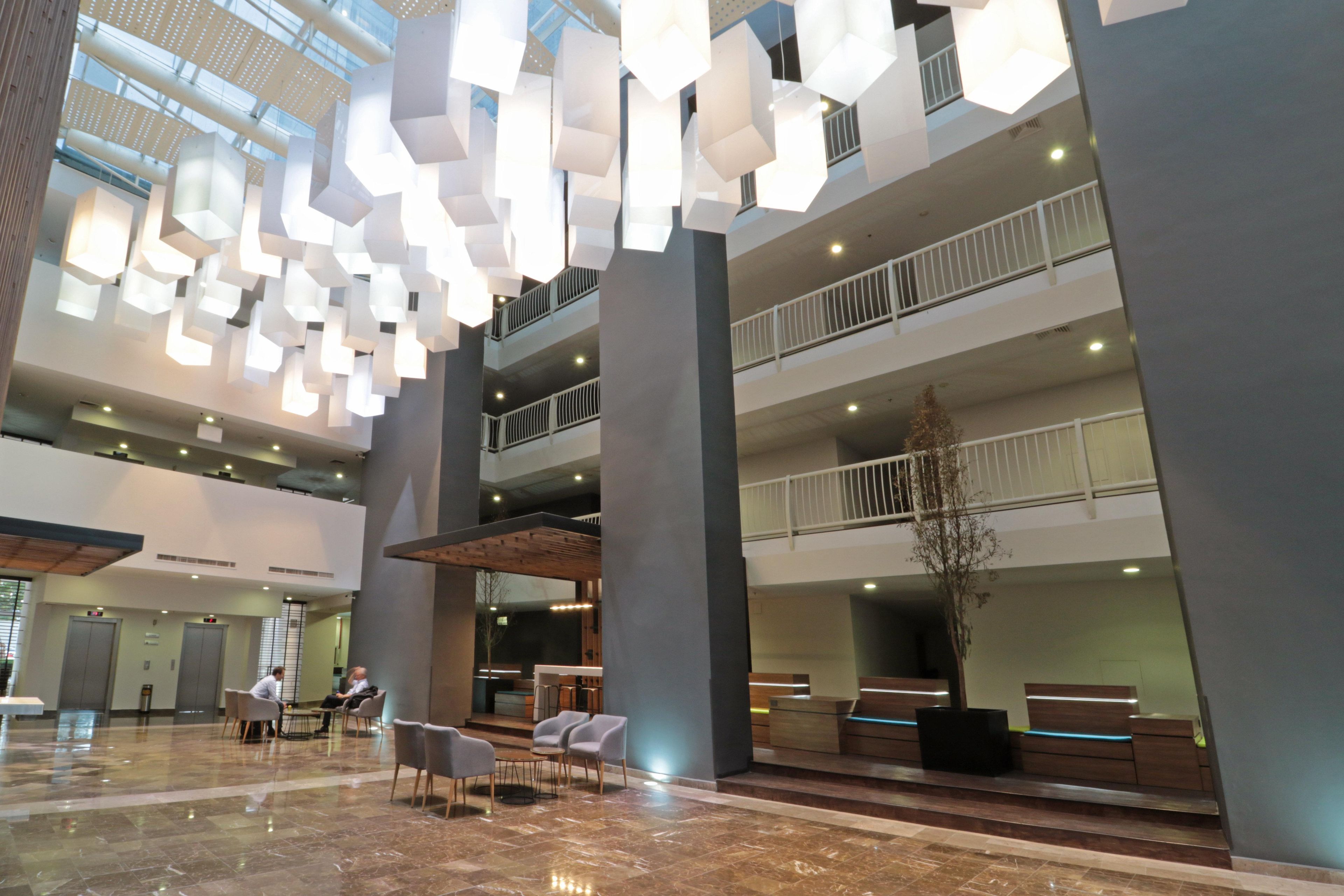 A spacious lobby with a high ceiling, modern lighting fixtures, and a seating area.