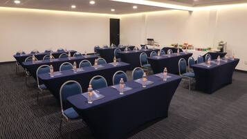 A conference room with multiple tables, chairs, and water bottles.