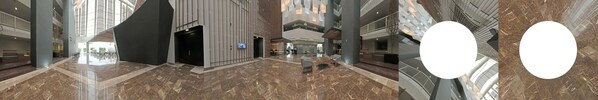 A spacious lobby with high ceilings, marble flooring, and modern furnishings.