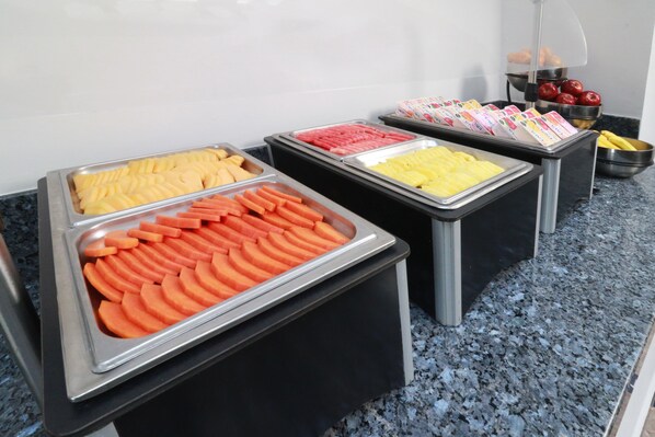 Buffet com diversos alimentos dispostos em bandejas.