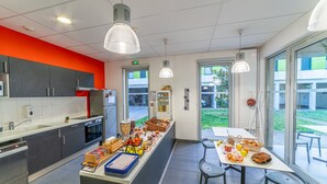 Eine moderne Küche mit einer zentralen Kochinsel, ausgestattet mit diversen Geräten und einem Sitzbereich mit Blick ins Freie.