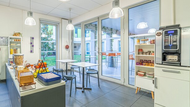 Eine moderne Küche mit einem großen Fenster, einer Kaffeemaschine und verschiedenen Küchengeräten.