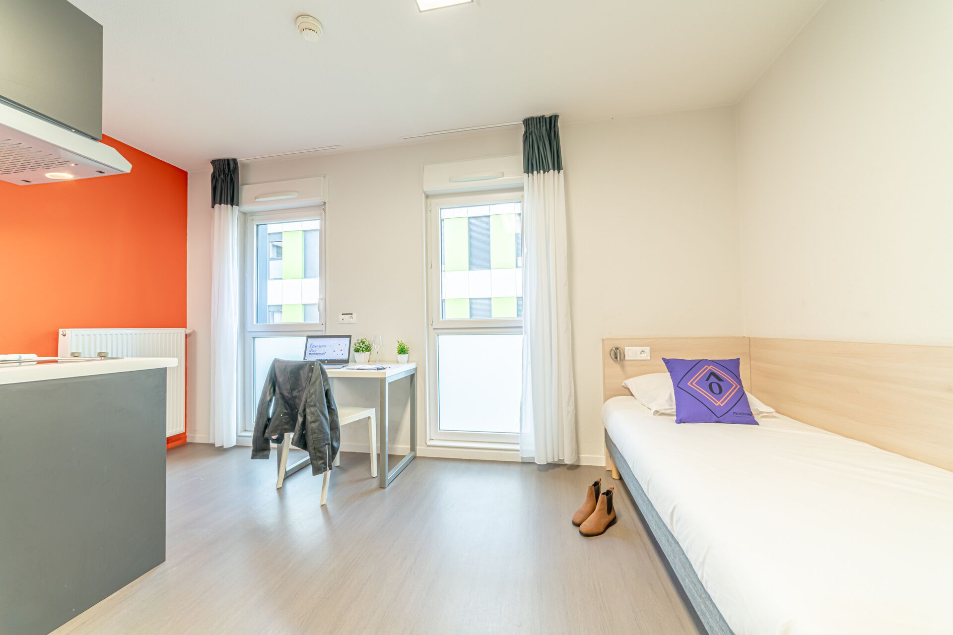 A hotel room with a bed, a desk, and a chair.