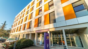 Ein modernes Hotel mit Schachbrettmuster-Fassade, einem sichtbaren Parkschild und einem deutlichen Eingang.