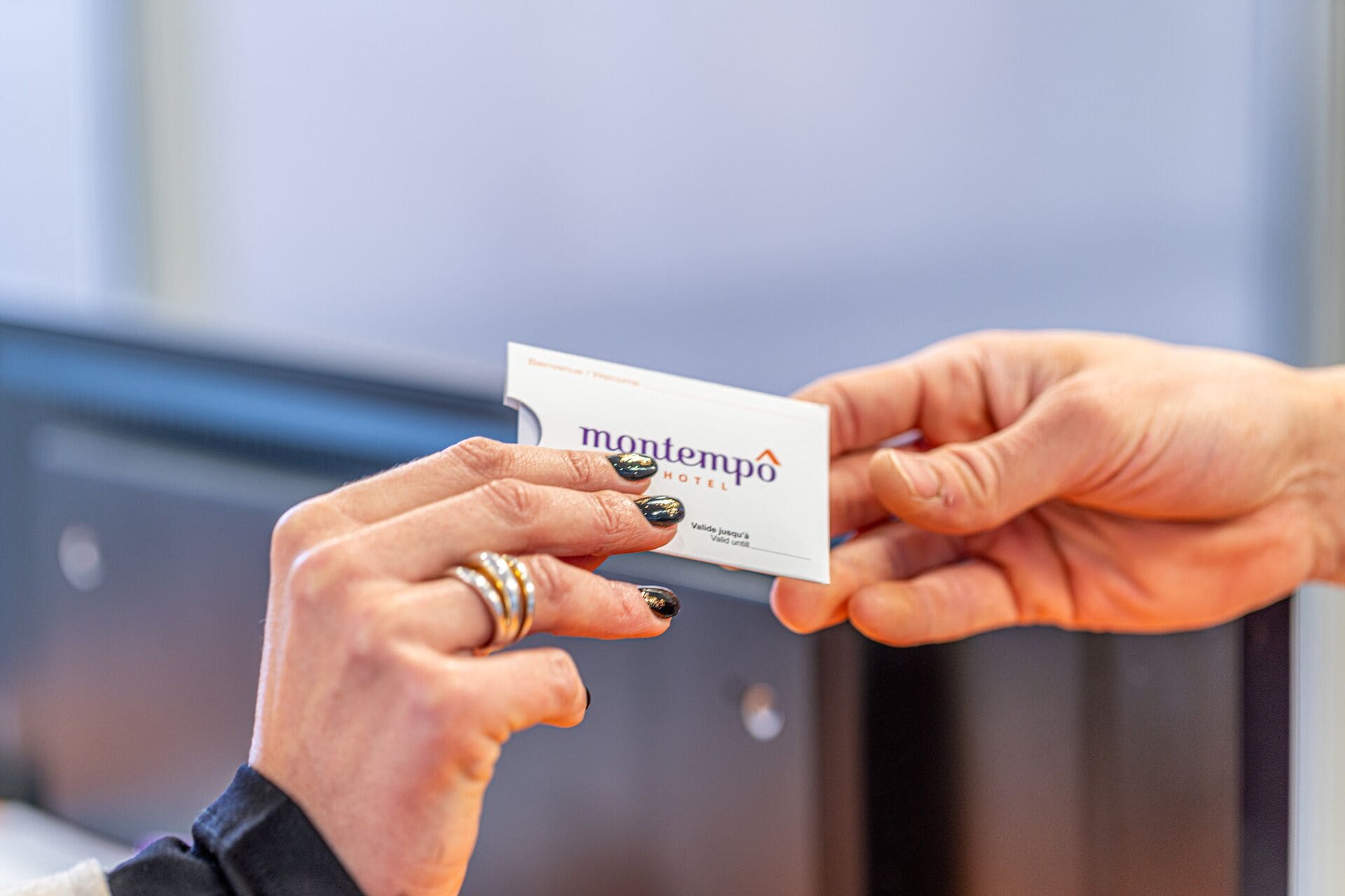 A hand holding a Montempo Hotel business card.