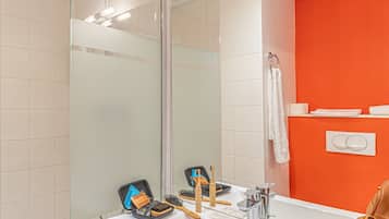 A modern bathroom with a large mirror, a white sink, and a glass shower enclosure.