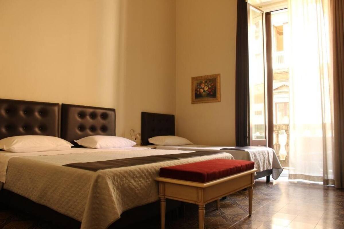 Een hotelkamer met twee bedden, een bank, een schilderij en uitzicht.