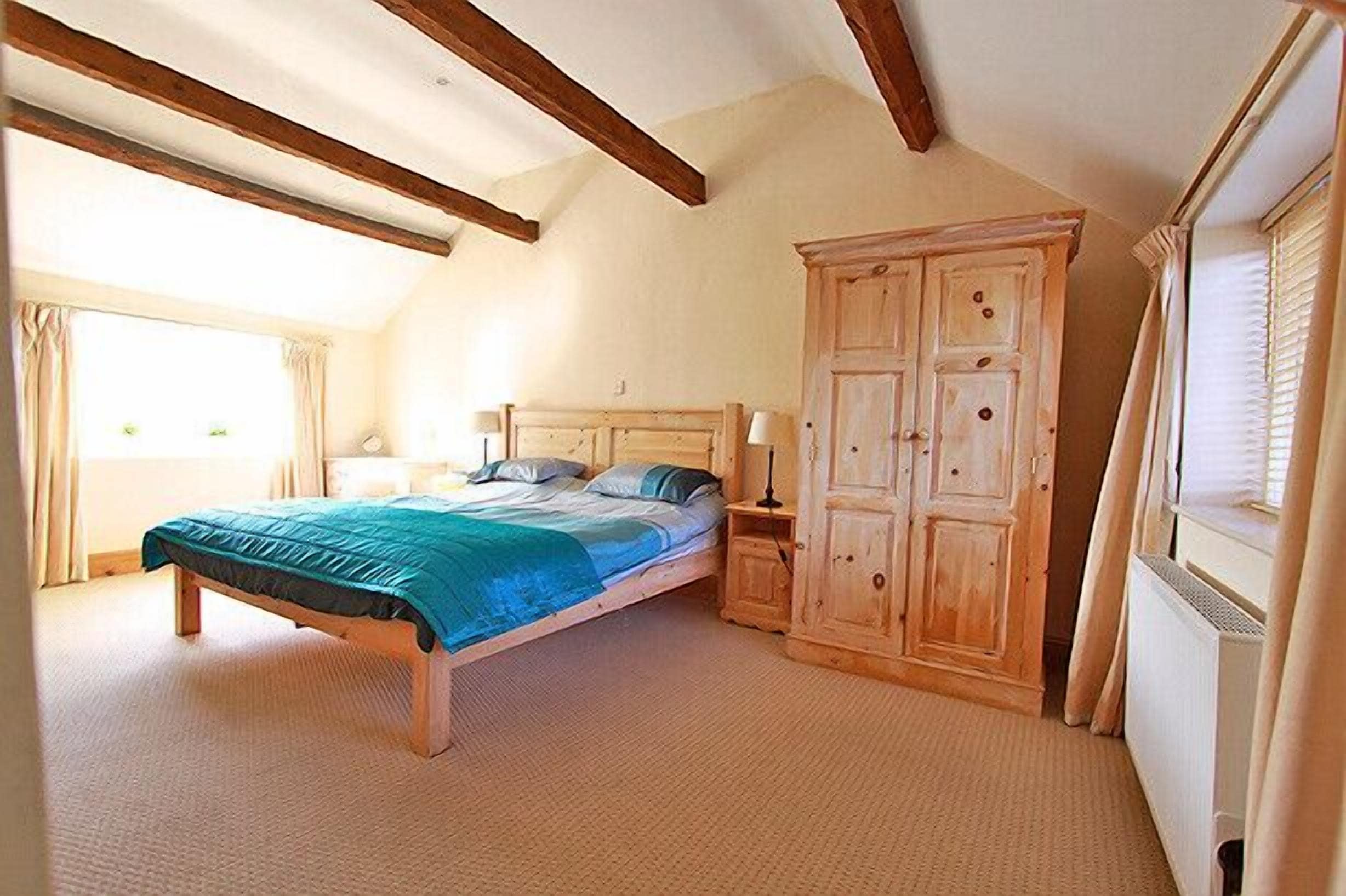 A bedroom with a bed, bedside tables, a wardrobe, and a window with curtains.