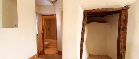 Un pasillo estrecho con un marco de puerta de madera y un baño pequeño al fondo.