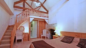 A bedroom with a wooden staircase, a fireplace, a bed, and a desk with a chair. - Centre of Britain Hotel & Restaurant (Haltwhistle)